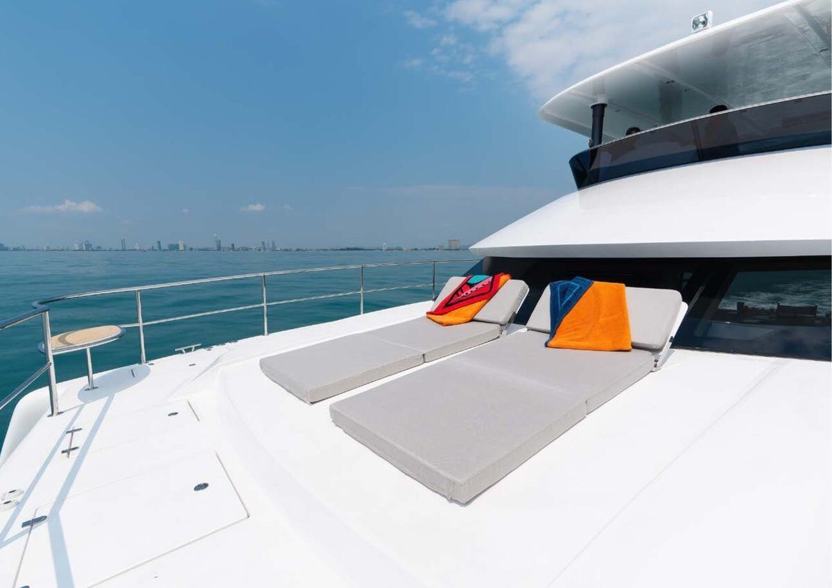 The 2024 Cora 48 Power Catamaran – Foredeck sun mattresses with the city skyline beyond – Avelis Yachts Singapore